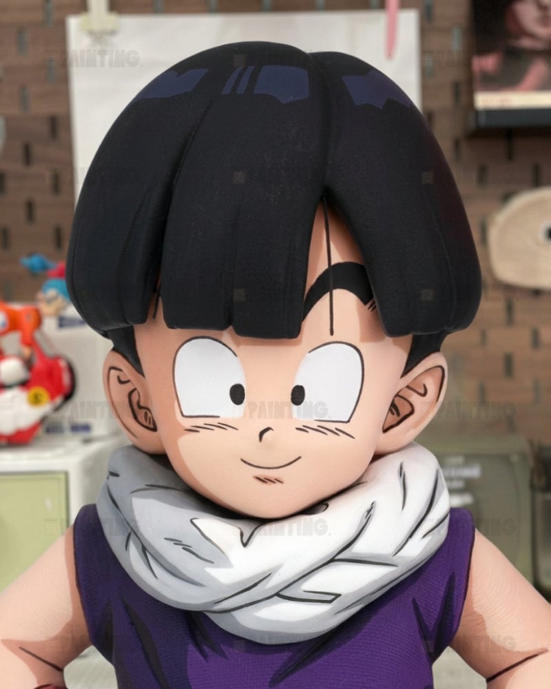 A close-up of an anime-style collectible figure or bust of a character with black hair, large white eyes, a white scarf, and a purple sleeveless top, shown against an indoor blurred background.