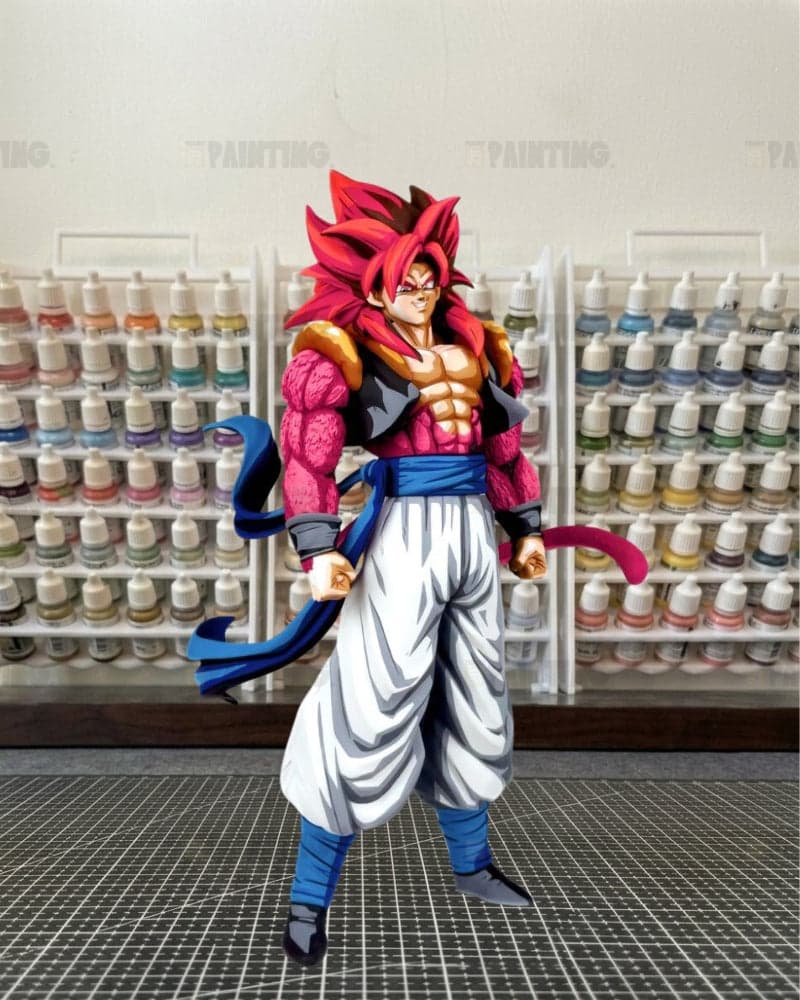 A detailed anime collectible figure of a Super Saiyan character with spiky red hair, wearing a pink and black bodysuit, white pants, and blue sash and boots, posed in front of shelves filled with paint bottles.