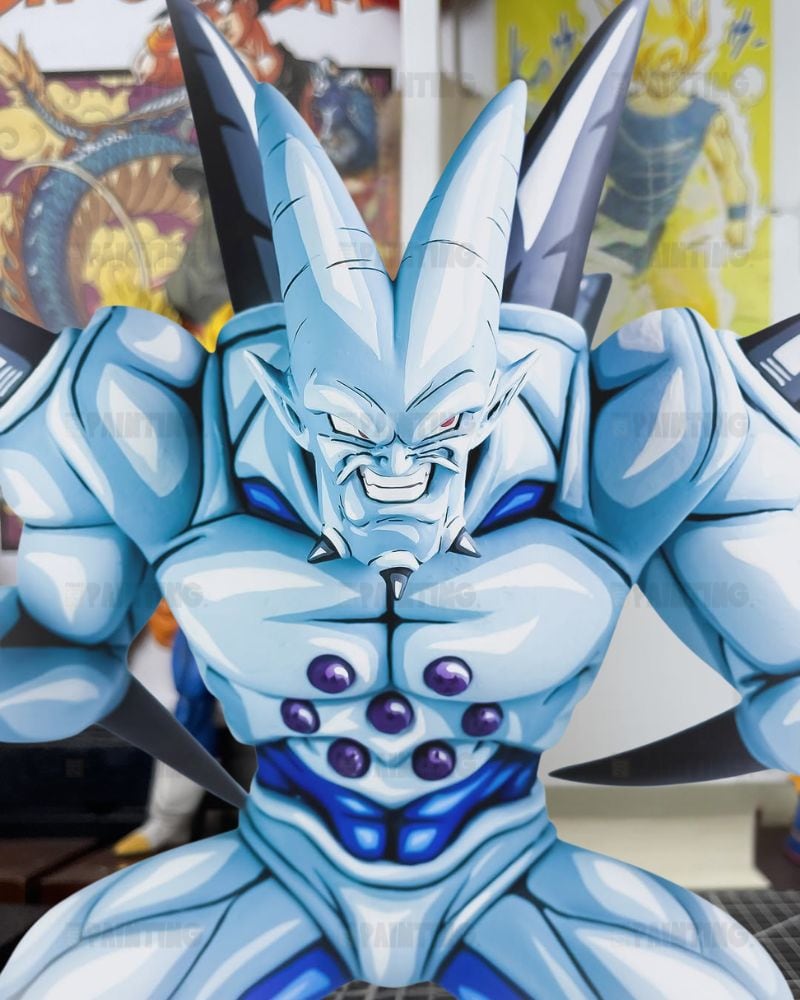 A close-up of a light blue anime character statue or collectible figure with sharp angular armor, dark gray spikes, and purple gem-like details on the chest, photographed indoors with blurred posters in the background.