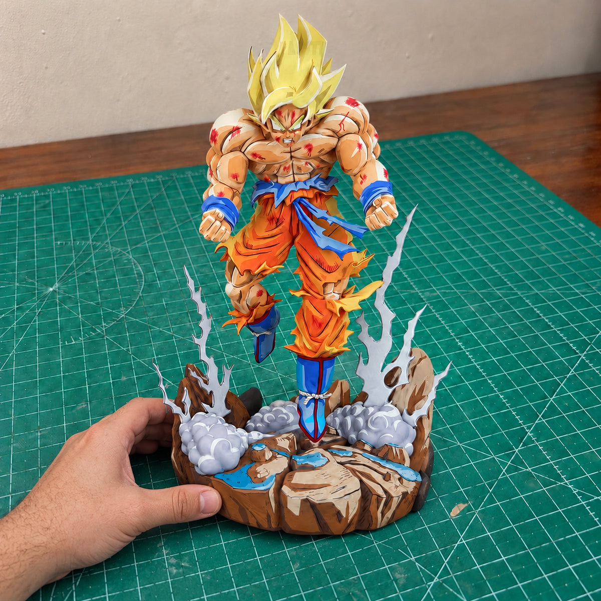 Comic Colour Super Saiyan Goku — base resting on the workbench, steadied by one hand