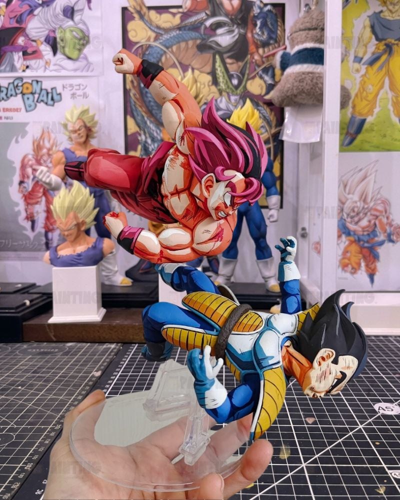 A Dragon Ball Z anime action figure set displayed on a clear stand, held by a hand in a collector's room with Dragon Ball posters and other figures in the background.