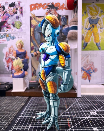 A custom-painted Dragon Ball figure of Frieza with blue, white, and orange armor, standing on a black gridded cutting mat in a collector's room with Dragon Ball posters in the background.