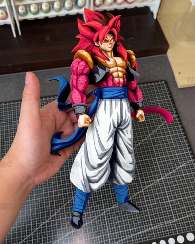 A hand holds a detailed anime figurine resembling Super Saiyan Gohan from Dragon Ball, featuring spiky red hair, a pink and black bodysuit, white pants, and blue accents, set against a tabletop background with a gridded mat.