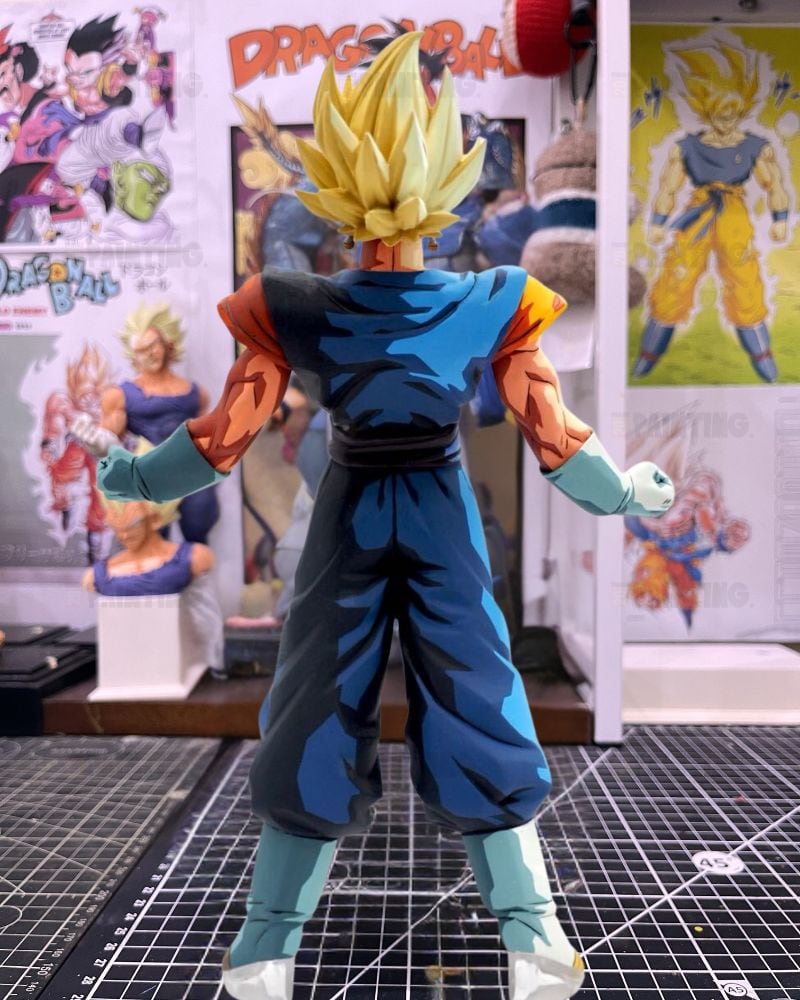 A Super Saiyan Gohan action figure from Dragon Ball Z, shown from the back on a black gridded cutting mat with Dragon Ball posters in the background.