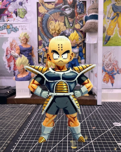 Dragon Ball figure of a character in a dark blue and gold armor pose, standing on a cutting mat with Dragon Ball posters in the background.