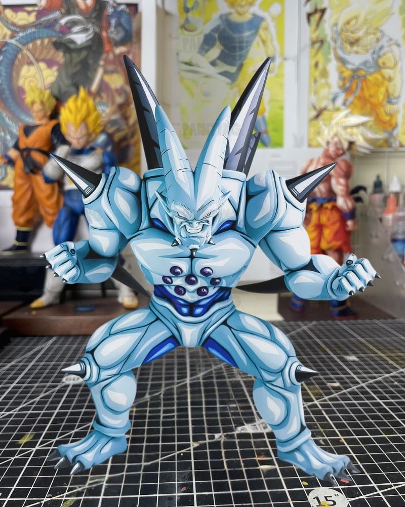 A light blue and white anime action figure with dark metallic spikes on its head and shoulders, posed on a gridded cutting mat with other collectible figures blurred in the background.