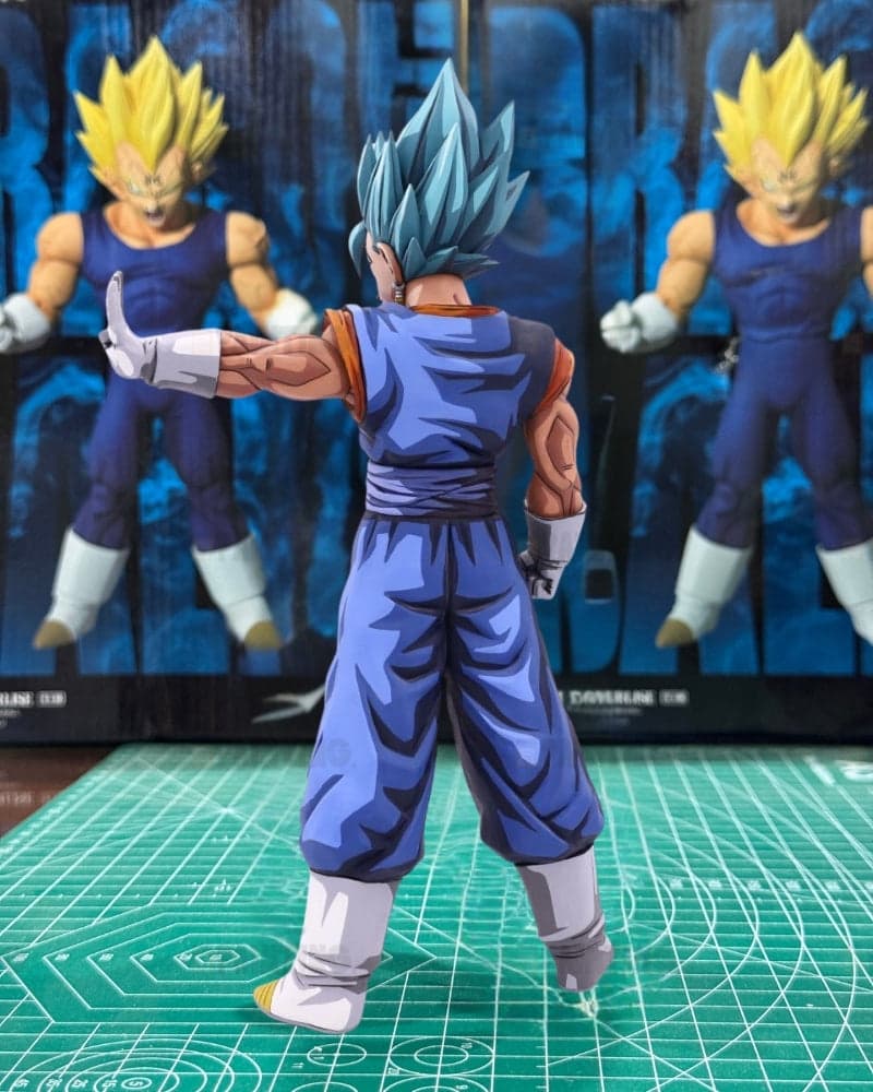 A Super Saiyan Gohan action figure shown from the back, wearing a blue and orange gi with spiky blue hair, standing on a green cutting mat in front of its original packaging box.