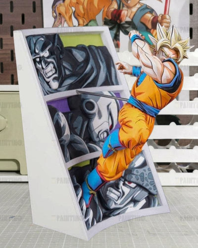 A 3D pop-up cardboard art piece featuring characters from Dragon Ball Z, including Goku in his Super Saiyan form and a dark robotic character, set against a white slatted background.