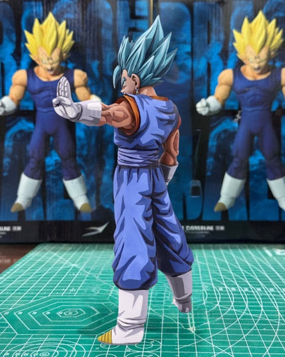 A Super Saiyan Gohan action figure posed on a green cutting mat, with two larger figures standing behind it against a blue backdrop.
