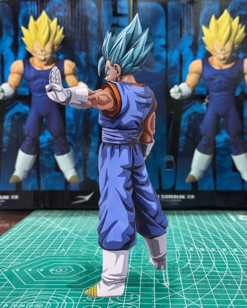 A Super Saiyan Gohan action figure posed on a green cutting mat, with two larger figures standing behind it against a blue backdrop.