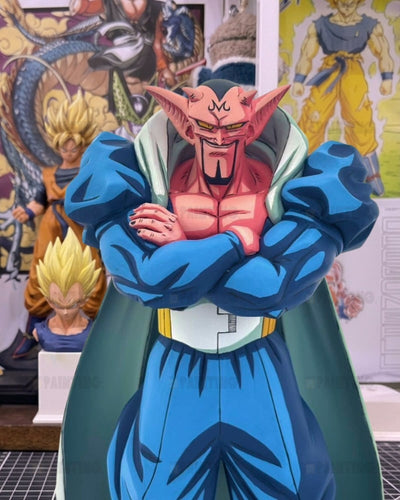 A detailed collectible statue of the anime character Cell from Dragon Ball Z, standing with arms crossed. The statue is set against a background of other Dragon Ball Z busts and posters.