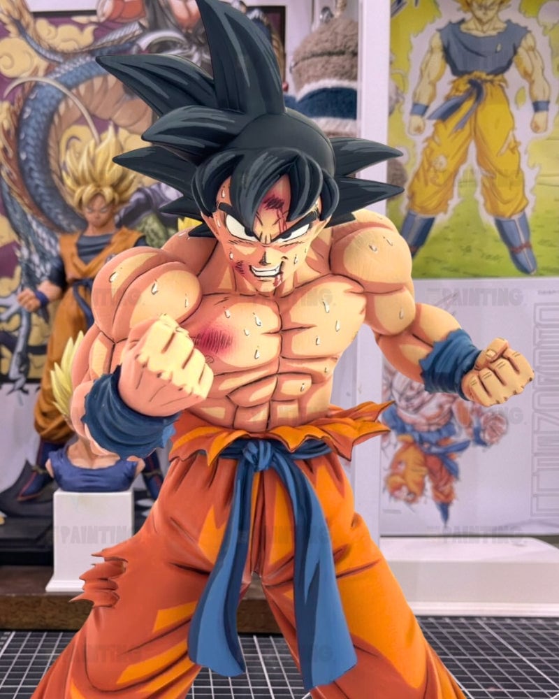 A detailed collectible figure of Goku from Dragon Ball Z in a fighting pose, featuring muscular definition, spiky black hair, an orange gi with a blue sash, and battle scars, set against a background of Dragon Ball posters and other figures.