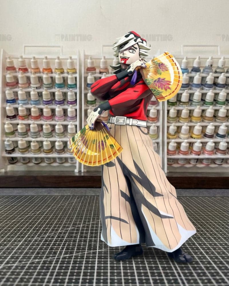 A collectible anime figure of Zenitsu Agatsuma from Demon Slayer, styled in a miniature craft room with shelves of paint bottles in the background.