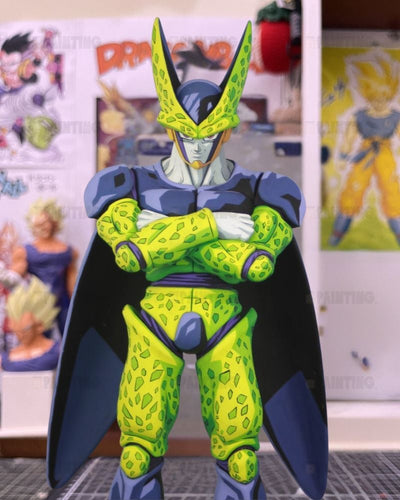 A Dragon Ball figure of Cell with arms crossed, featuring green and yellow patterned armor, a dark blue cape, and a blue helmet, set against a background of anime posters.