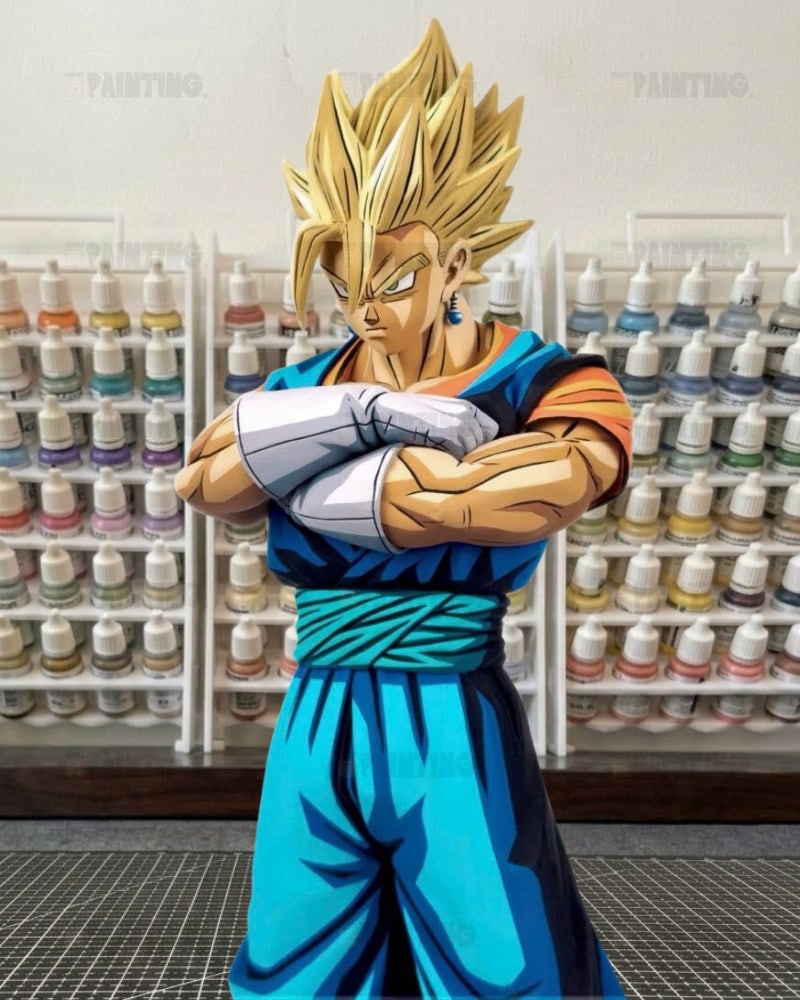 A collectible anime figure of Vegetto in a Super Saiyan form, standing with arms crossed in front of shelves filled with paint bottles.