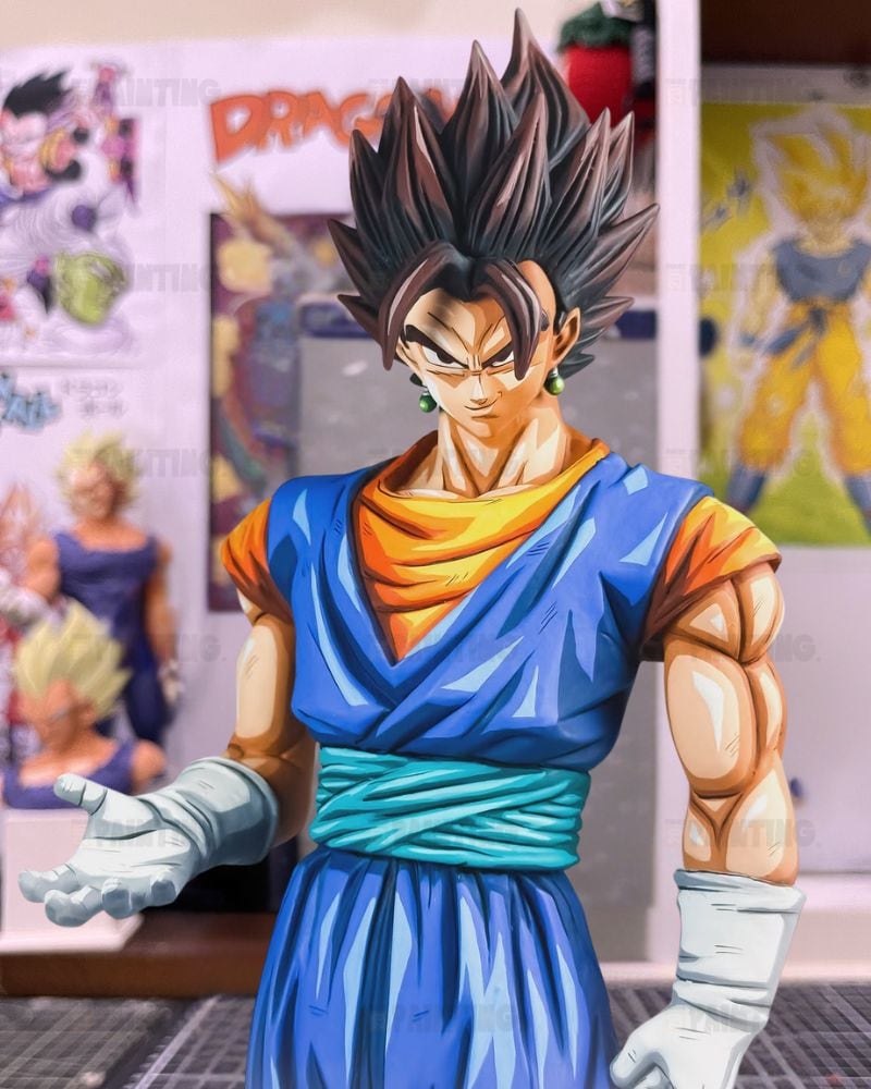 A detailed anime figurine of Goku in his Super Saiyan form, wearing his classic blue and orange gi with a teal sash, standing in a collector's room with Dragon Ball posters in the background.