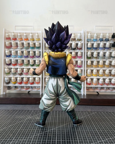A painted Dragon Ball Z anime figure of Vegetto in a spiky dark purple and black Super Saiyan form, shown from the back on a cutting mat with shelves of paint bottles in the background.