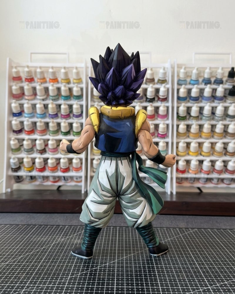 A painted Dragon Ball Z anime figure of Vegetto in a spiky dark purple and black Super Saiyan form, shown from the back on a cutting mat with shelves of paint bottles in the background.