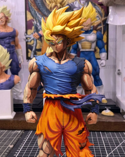 A detailed collectible figurine of Goku in a Super Saiyan form, wearing a torn blue top and orange pants, standing in a display room with other anime figures in the background.
