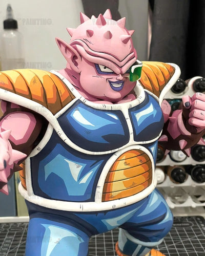 A detailed Dodoria collectible figurine of a pink spiky character from Dragon Ball Z, wearing a blue and orange battle armor vest, shown in a workshop setting.