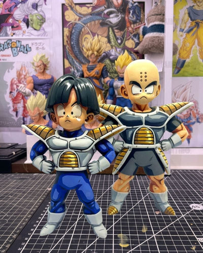 Two Dragon Ball figurines posed together on a cutting mat, with anime posters in the background.