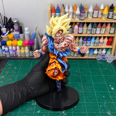 Super Saiyan Son Goku Jump 50th Anniversary Figure Repaint — held securely in one gloved hand in the workshop