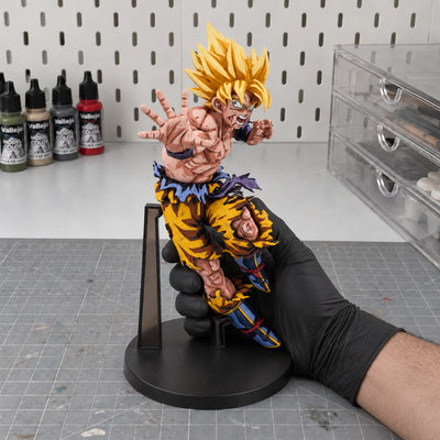 Dragon Ball Son Goku Tenkaichi Budokai Figure Repaint — held securely in one gloved hand in the workshop