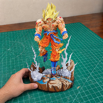 Comic Colour Super Saiyan Goku — base resting on the workbench, steadied by one hand