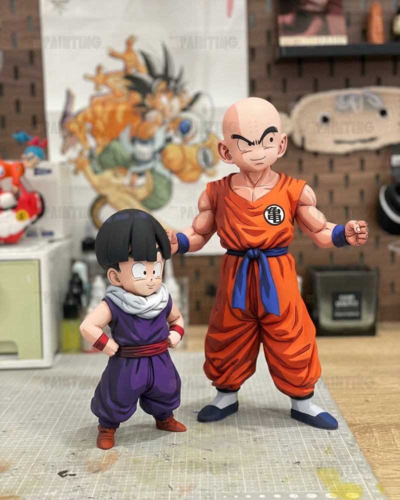 Two Dragon Ball Z action figures, Master Roshi and Gohan, standing on a gridded cutting mat in a hobby room setting.