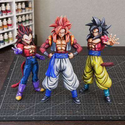 SSJ4 Goku, Vegeta and Gogeta figures standing together in a painting workshop
